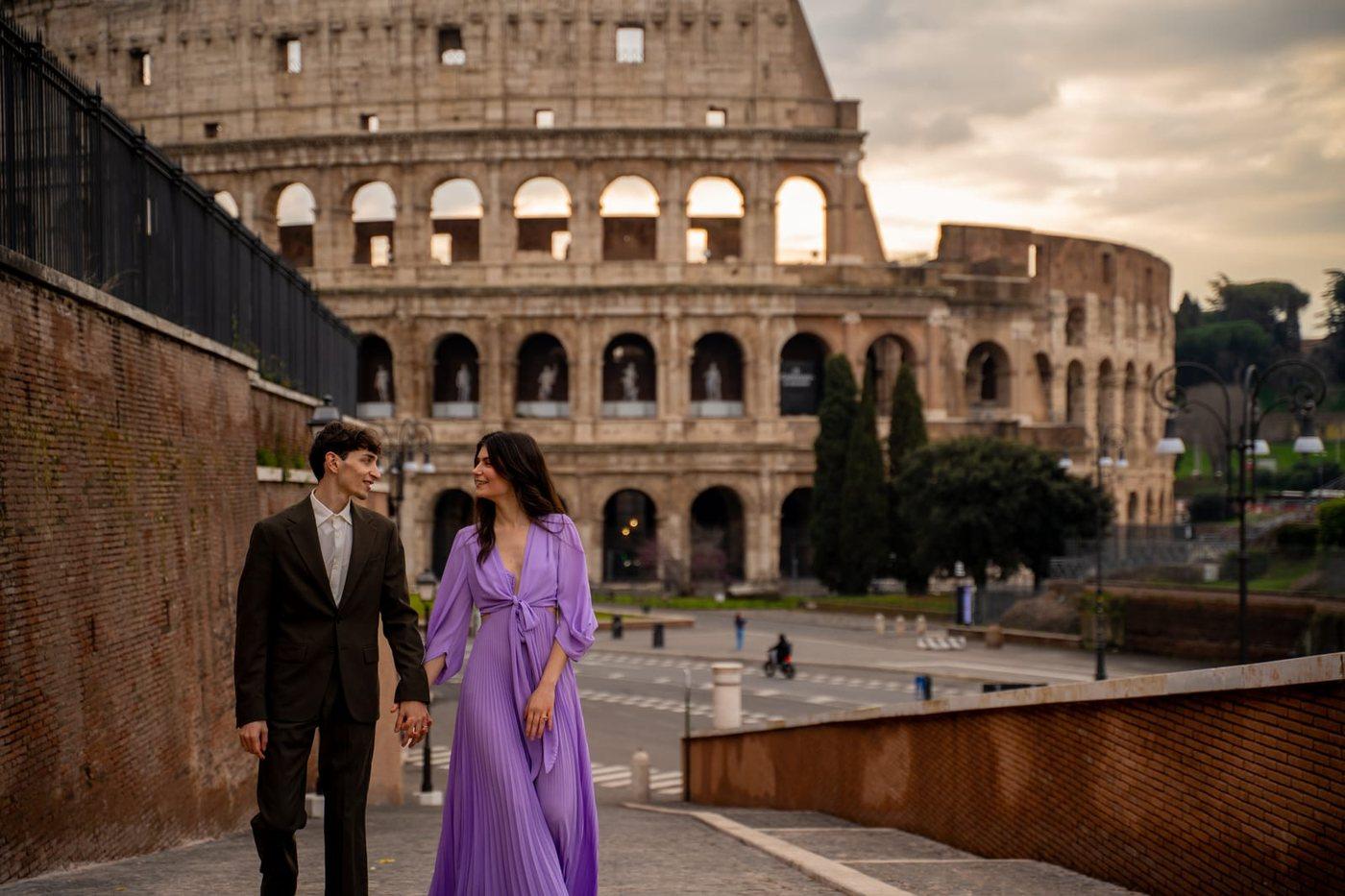 A couple walking together in Rome with the Colosseum behind them