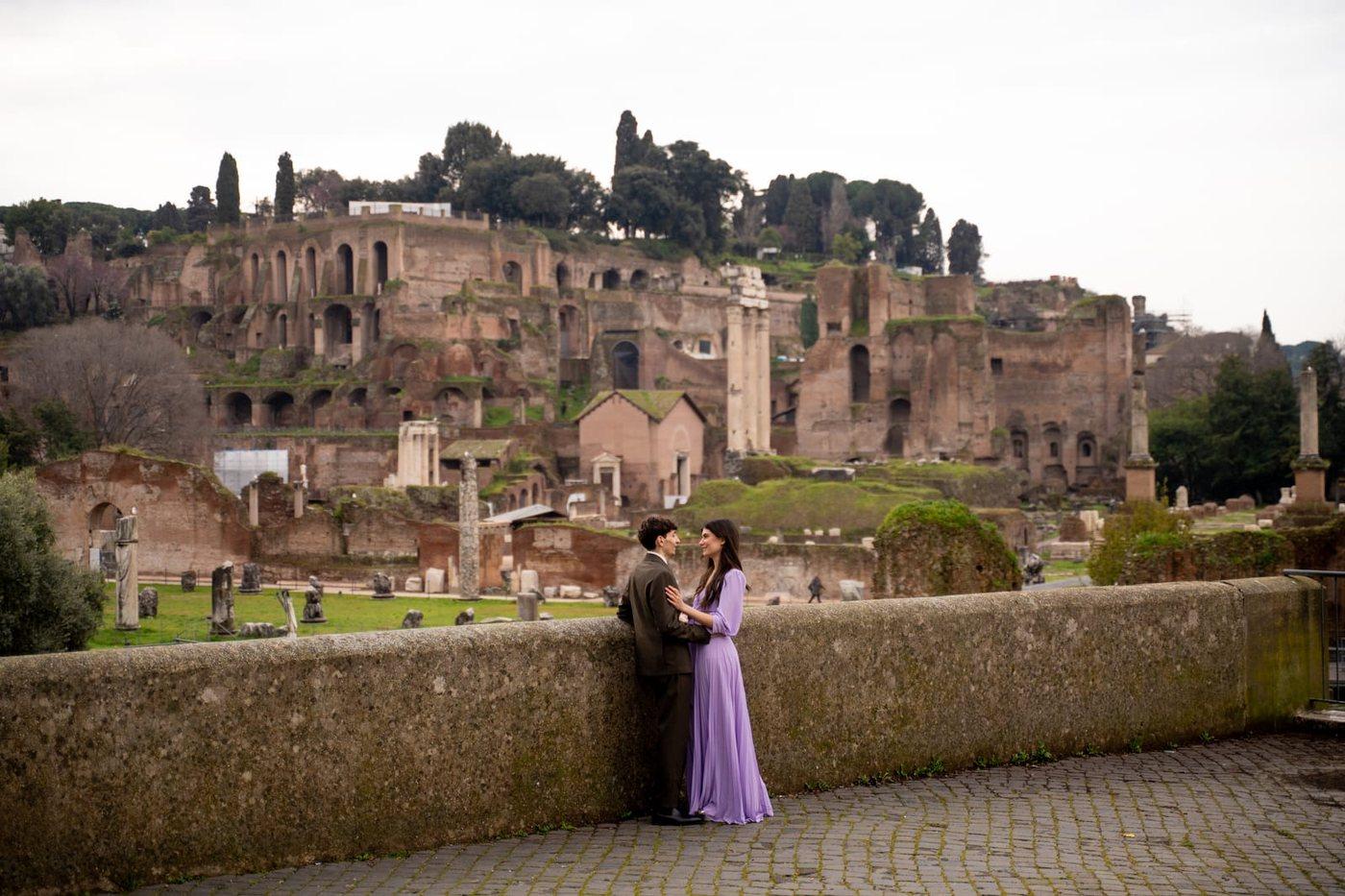 A couple on the wall above the Roman Forum with the ruins and the Palatine behind