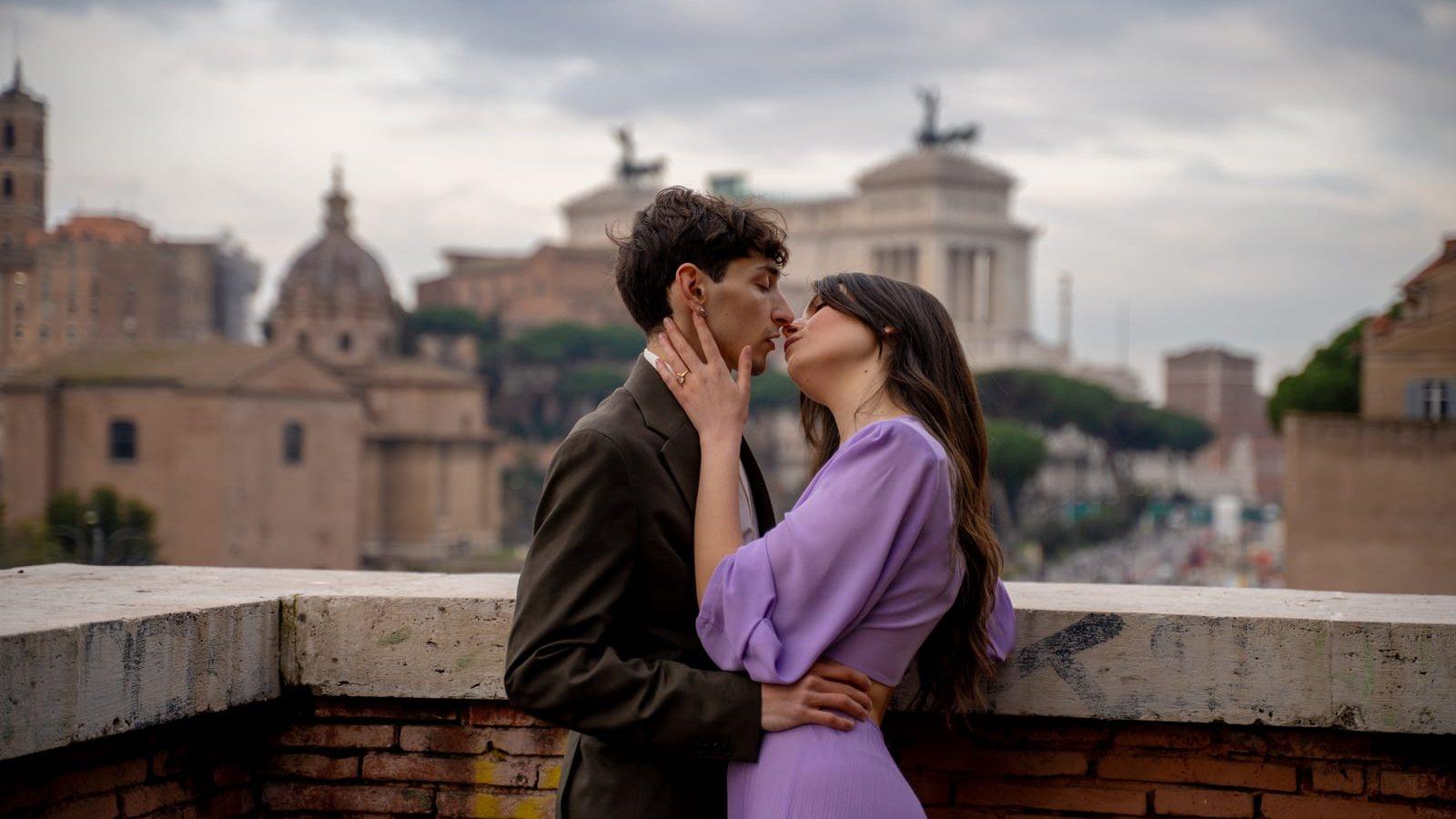 A couple on a Rome terrace at dusk with the city's domes behind them